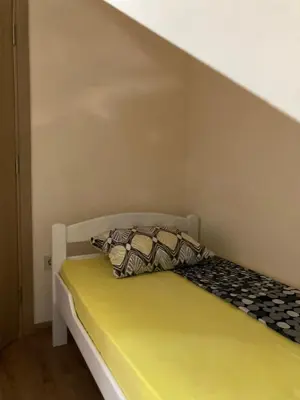 a bed in a small room with yellow sheets and pillows at Podgorica-Downtown in Podgorica