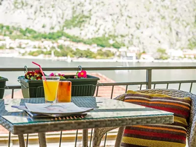 a table with a drink and a basket of flowers on a balcony at Green Home Apartments in Kotor