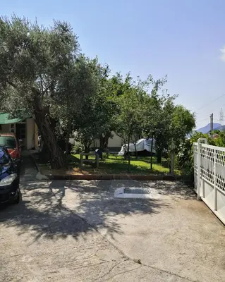 a parking lot with a fence and a tree at Apartment Dukić in Bar