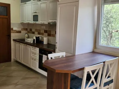 a kitchen with a wooden table and white cabinets at Apartment Dukić in Bar
