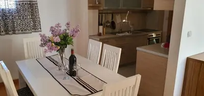 a white dining room table with a vase of flowers on it at Elena in Bar
