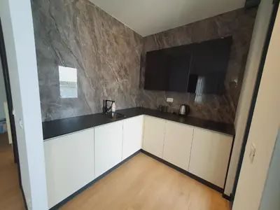 a kitchen with white cabinets and a flat screen tv at Prestige Central apartments - Rafailovici in Budva