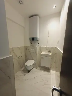 a white bathroom with a toilet and a sink at Prestige Central apartments - Rafailovici in Budva