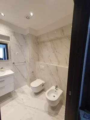 a white bathroom with a toilet and a sink at Prestige Central apartments - Rafailovici in Budva