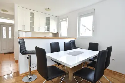 a dining room with a white table and black chairs at Apartments Budva Center 2 in Budva