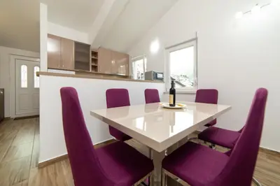 a dining room table with purple chairs and a bottle of wine at Apartments Budva Center 2 in Budva
