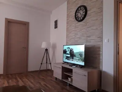 a television on a dresser with a clock on a wall at Adriatic Sunset House in Petrovac na Moru