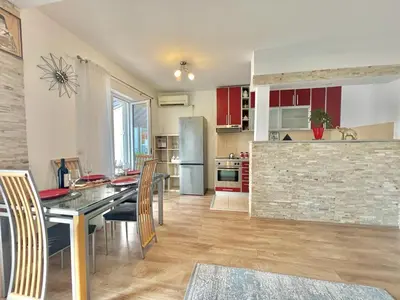 a kitchen with red cabinets and a table with chairs at Parapid Apartments Budva in Budva
