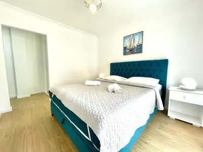 a bedroom with a bed with a blue headboard at Parapid Apartments Budva in Budva