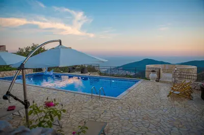 a swimming pool with an umbrella and a view at Villa Marija **** with private pool in Budva