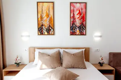 a bedroom with a bed with three paintings on the wall at Apartments Hoxha in Ulcinj