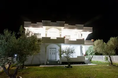 a white house with a white door at night at Apartments Hoxha in Ulcinj