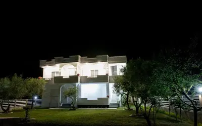 a large white house at night with trees in front at Apartments Hoxha in Ulcinj