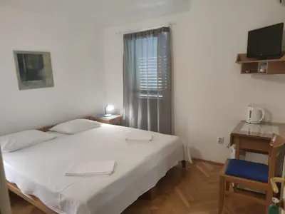 a bedroom with a white bed and a television at Apartmani Soljaga in Petrovac na Moru