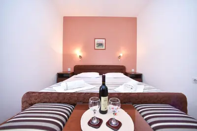 a room with a bed with a bottle of wine on a table at Apartmani Soljaga in Petrovac na Moru
