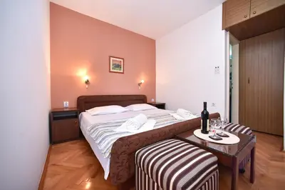 a bedroom with a large bed and a table with a chair at Apartmani Soljaga in Petrovac na Moru