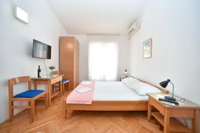 a bedroom with a bed and a desk and a chair at Apartmani Soljaga in Petrovac na Moru