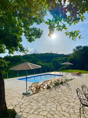 a swimming pool with an umbrella and tables and chairs at BIO VILLAS in Podgorica