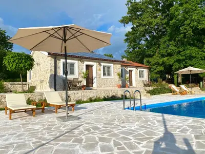 a patio with an umbrella and chairs next to a pool at BIO VILLAS in Podgorica