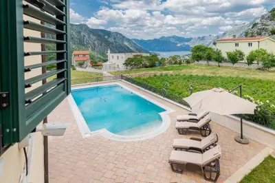 a swimming pool with lounge chairs and an umbrella at Sunset Rose in Kotor
