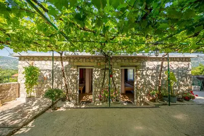 a stone house with a tree in front of it at Ethno house OSOBAK in Virpazar