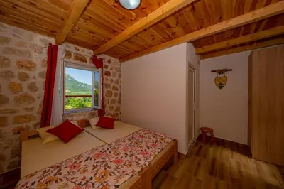 a bedroom with a bed and a window in a room at Ethno house OSOBAK in Virpazar