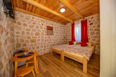 a small bedroom with a bed and a table at Ethno house OSOBAK in Virpazar