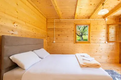 a bedroom with a bed in a wooden cabin at Lovcen mountain cottages in Vratnica