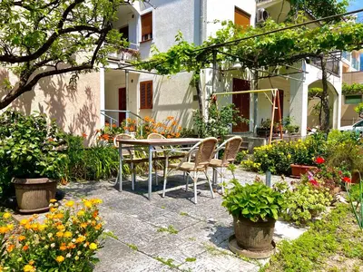 a patio with a table and chairs and flowers at Garden House Budva in Budva