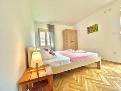a bedroom with a large bed with a pink blanket at Garden House Budva in Budva