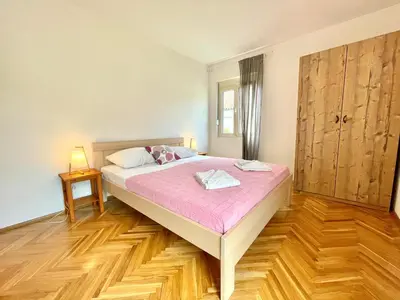 a large bed in a room with a wooden floor at Garden House Budva in Budva