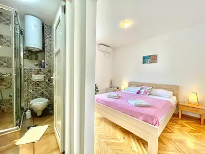 a bedroom with a bed and a bathroom with a shower at Garden House Budva in Budva