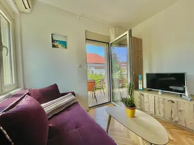 a living room with a purple couch and a table at Garden House Budva in Budva