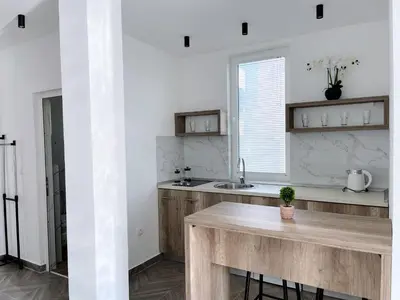 a kitchen with white walls and a wooden counter top at Guest House Koliqi - Hotel & Apartments in Ulcinj
