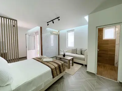a white bedroom with a bed and a couch at Guest House Koliqi - Hotel & Apartments in Ulcinj