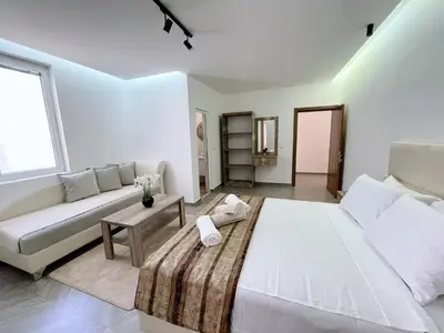 a white bedroom with a large bed and a couch at Guest House Koliqi - Hotel & Apartments in Ulcinj