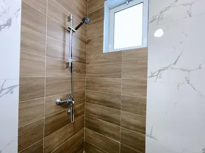 a shower with a glass door and a window at Guest House Koliqi - Hotel & Apartments in Ulcinj