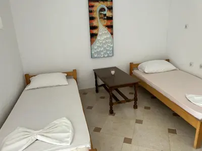 two beds in a room with a table and a picture at Apartments Doda in Ulcinj