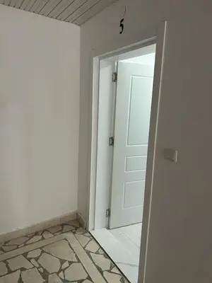 an empty room with a white door and a tile floor at Apartments Doda in Ulcinj