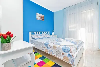 a blue bedroom with a bed and a white table at Apartment Milos in Kotor
