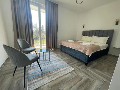 a bedroom with a bed and a chair and a window at Belami luxury apartments in Ulcinj
