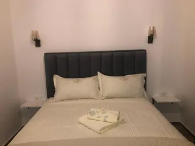 a bed with a black headboard and two tables at Belami luxury apartments in Ulcinj