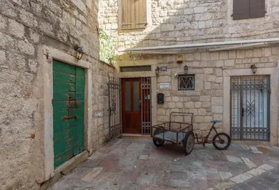 a bike parked next to a building with a green door at Old Town St Tryphon Apartment in Kotor