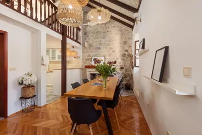 a kitchen and dining room with a wooden table and chairs at Old Town St Tryphon Apartment in Kotor