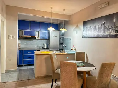 a kitchen with blue cabinets and a table with chairs at Apartman M&U in Petrovac na Moru