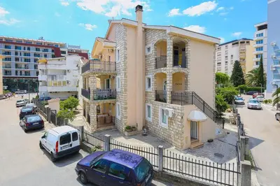 a building with cars parked in a parking lot at Apartman AS in Budva