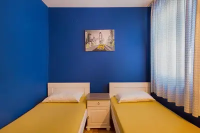 two beds in a room with a blue wall at Apartman AS in Budva