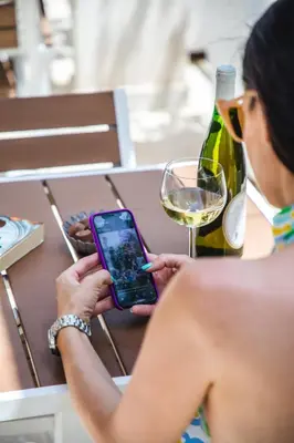 a woman holding a cell phone and a glass of wine at Villa Katarina in Budva