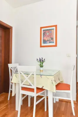 a white table and chairs with a vase of flowers on it at Modern Studio 200m from the Beach in Budva