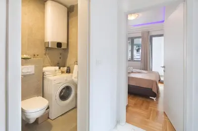 a bathroom with a toilet a sink and a washing machine at City center lux apartment in Budva